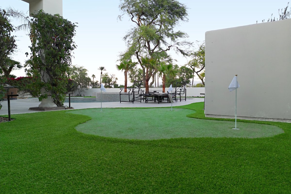 Artificial turf lawn and putting green with flags in a desert backyard