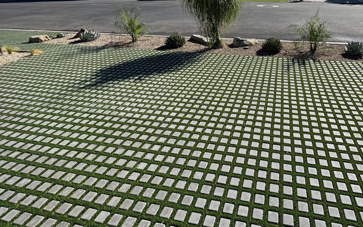 Concrete grid pavers with turf joints beside a gravel bed of desert plants
