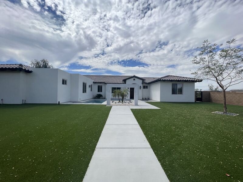 Turf lawn and walkway leading to a modern home under a dramatic sky