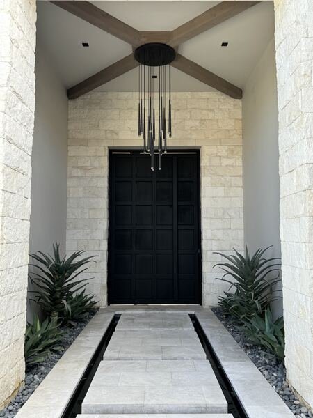 Symmetrical entry walk framed by agave beds leading to a tall black front door